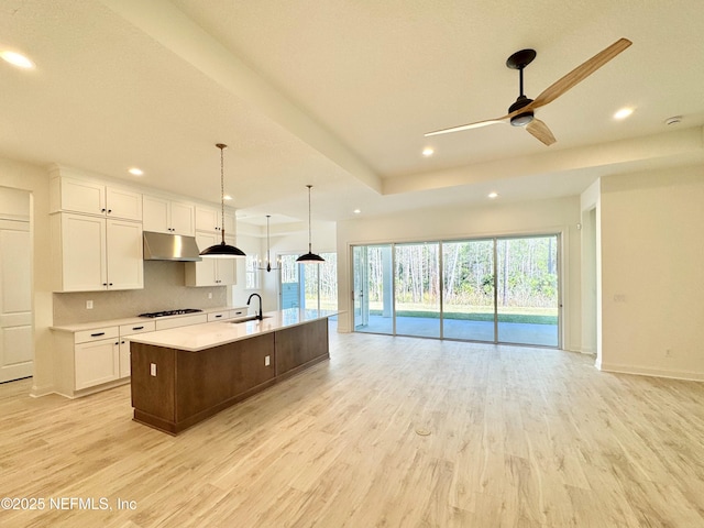 kitchen featuring white cabinetry, gas cooktop, sink, and a large island with sink