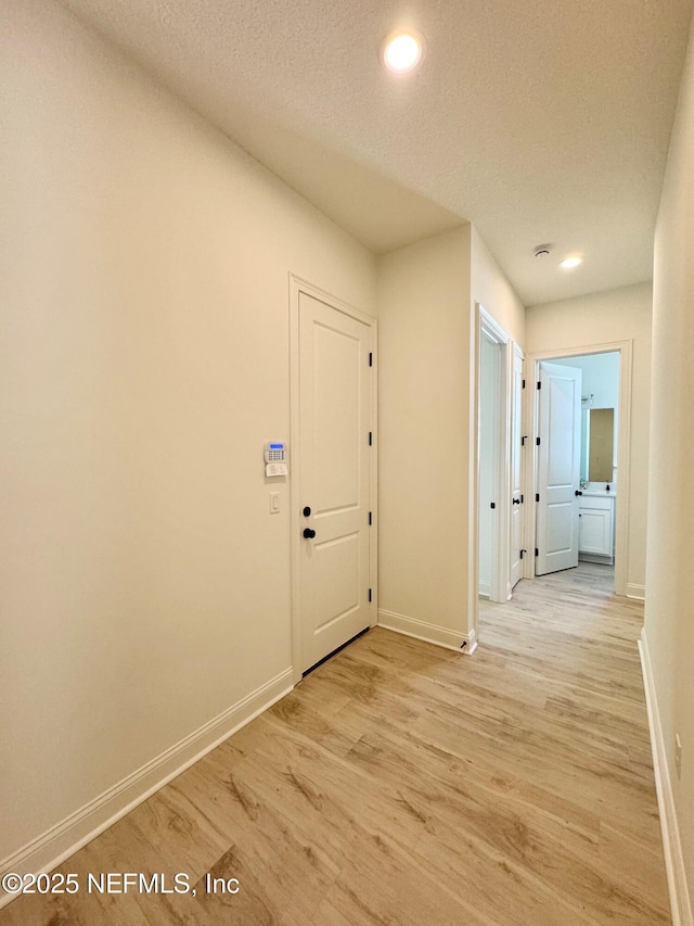 hallway featuring a textured ceiling and light hardwood / wood-style floors