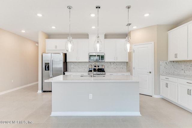 kitchen featuring a kitchen island with sink, decorative light fixtures, white cabinetry, and appliances with stainless steel finishes