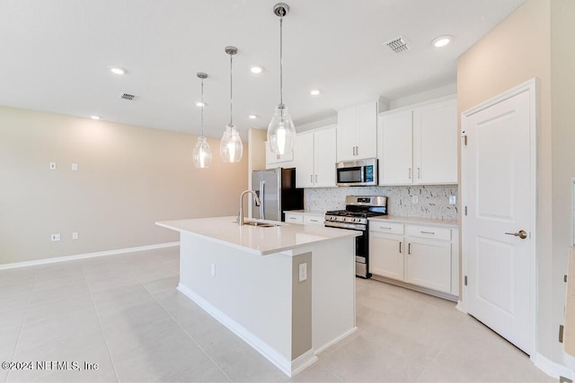 kitchen featuring white cabinetry, appliances with stainless steel finishes, decorative light fixtures, and an island with sink