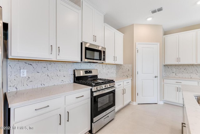 kitchen featuring white cabinetry, tasteful backsplash, light tile patterned floors, appliances with stainless steel finishes, and light stone countertops