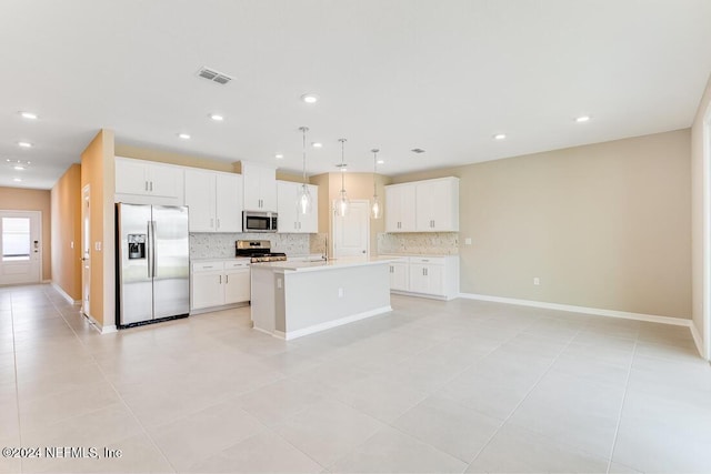 kitchen with stainless steel appliances, an island with sink, hanging light fixtures, and white cabinetry