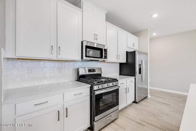 kitchen with tasteful backsplash, appliances with stainless steel finishes, light hardwood / wood-style floors, and white cabinets