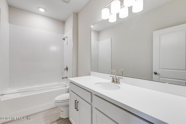 full bathroom with hardwood / wood-style floors, tiled shower / bath, toilet, and vanity