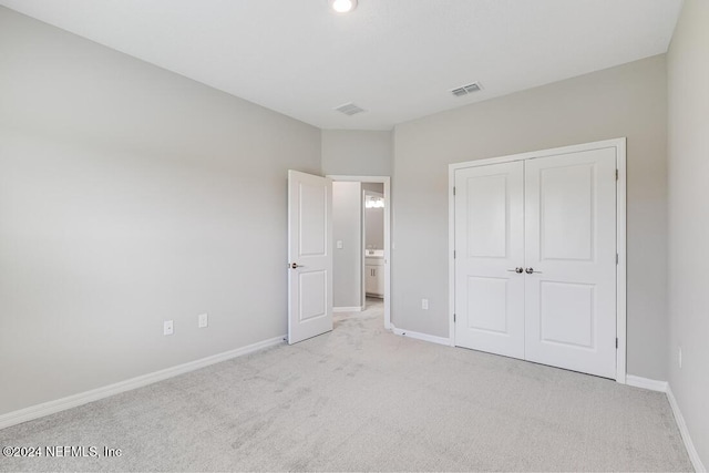 unfurnished bedroom with light carpet and a closet