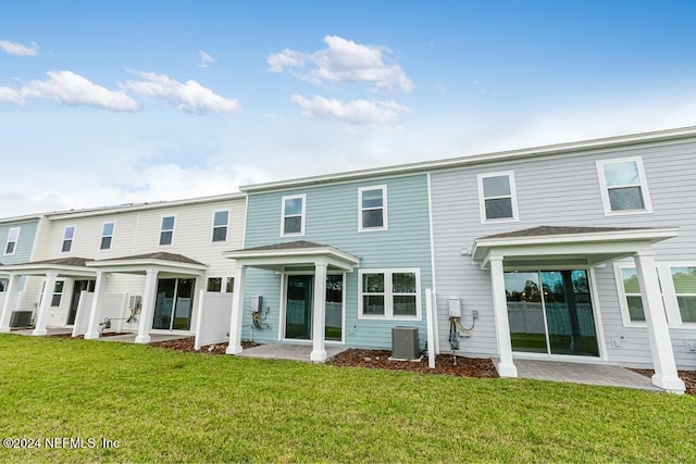 rear view of house featuring a lawn, cooling unit, and a patio