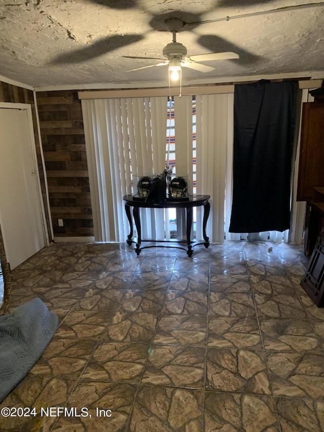 foyer entrance featuring a textured ceiling, ceiling fan, and stone flooring