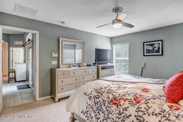 bedroom featuring ceiling fan, light carpet, and a textured ceiling