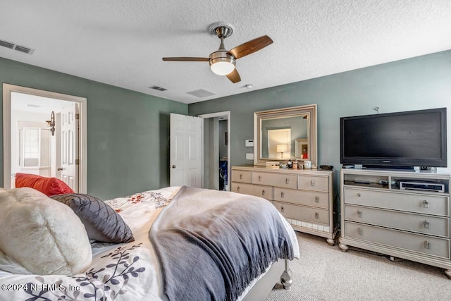 bedroom with ensuite bathroom, light carpet, ceiling fan, and a textured ceiling