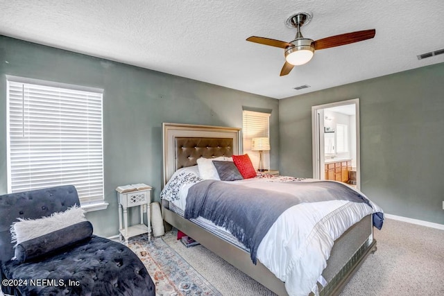 carpeted bedroom featuring ceiling fan, connected bathroom, and a textured ceiling