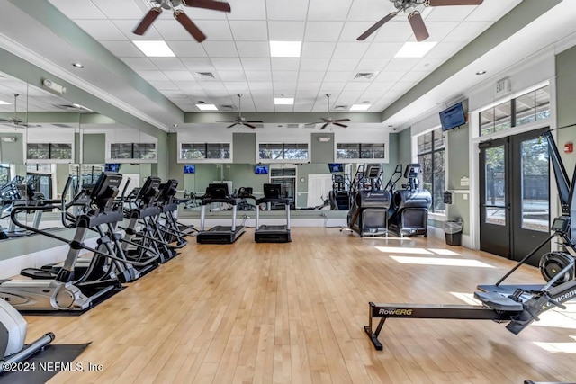 gym featuring ceiling fan, a paneled ceiling, light wood-type flooring, and french doors