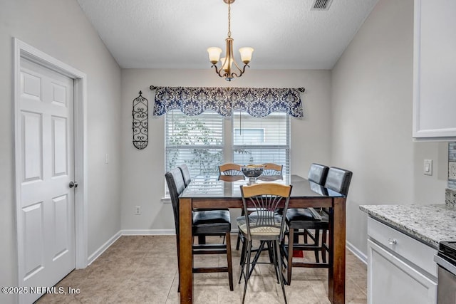 tiled dining space with an inviting chandelier and a textured ceiling