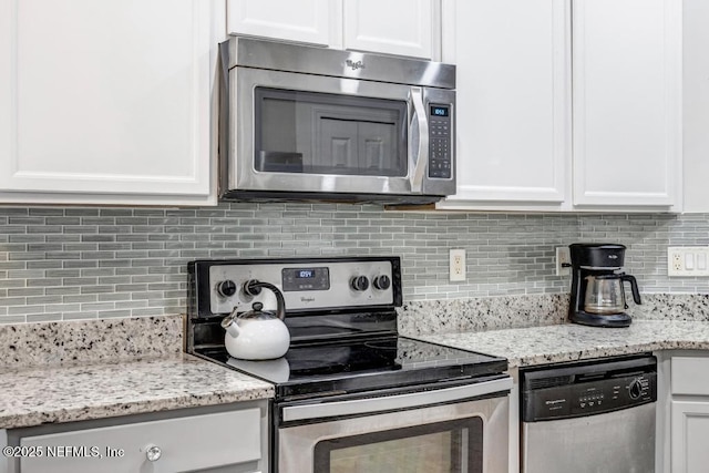 kitchen featuring stainless steel appliances, white cabinetry, light stone countertops, and tasteful backsplash