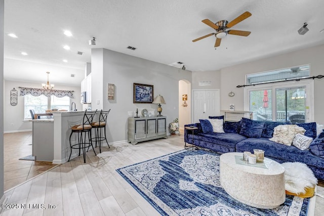 living room with sink, ceiling fan with notable chandelier, and light hardwood / wood-style flooring