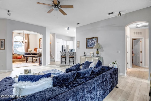 living room featuring ceiling fan with notable chandelier and light hardwood / wood-style floors