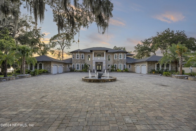 view of front of property featuring a garage, stone siding, and decorative driveway