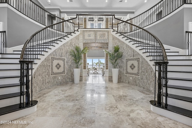 foyer entrance with marble finish floor, a high ceiling, stairway, and crown molding