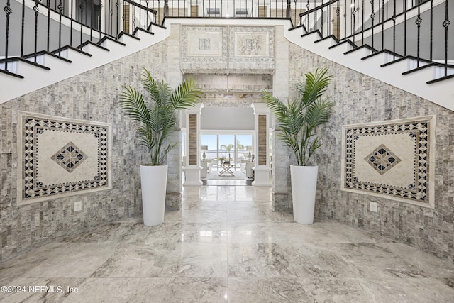 interior space featuring stairs, marble finish floor, a high ceiling, and ornate columns