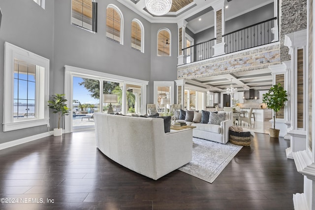 living area featuring coffered ceiling, baseboards, dark wood-type flooring, and a notable chandelier