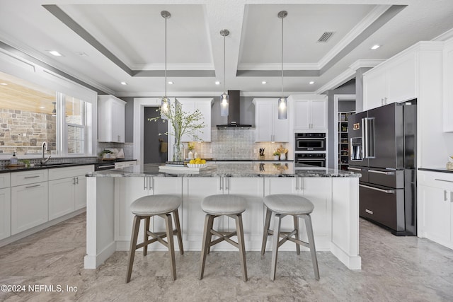 kitchen with dark stone counters, high end black fridge, wall chimney exhaust hood, and pendant lighting