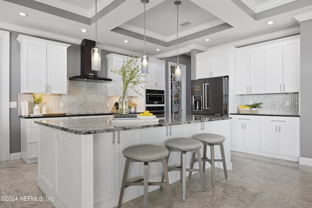 kitchen featuring wall chimney range hood, high end refrigerator, white cabinets, and a center island