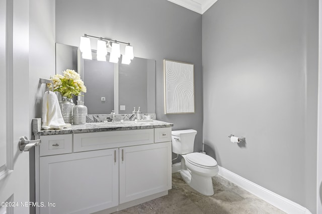 bathroom with toilet, vanity, and baseboards