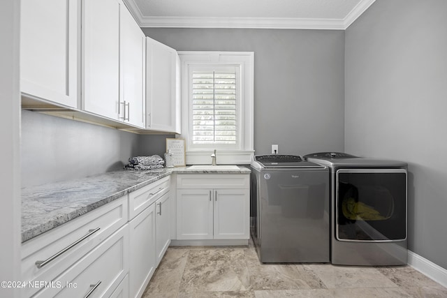 laundry area featuring ornamental molding, washing machine and clothes dryer, a sink, and cabinet space