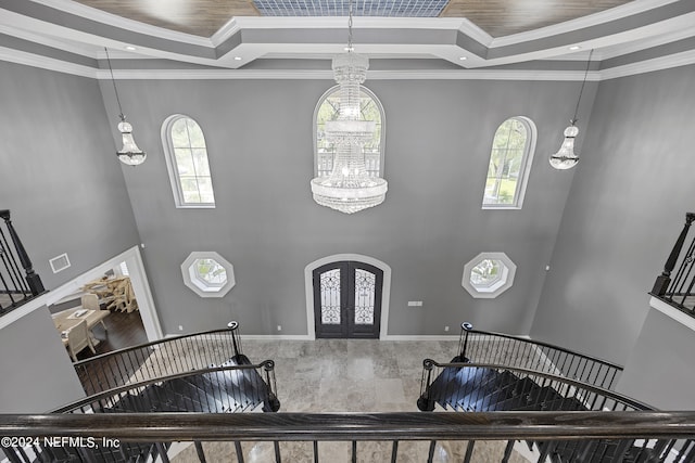 foyer with visible vents, a raised ceiling, arched walkways, an inviting chandelier, and french doors