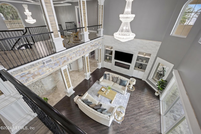 living room with a high ceiling, dark wood-style flooring, built in shelves, and a notable chandelier