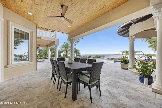 view of patio featuring a ceiling fan, outdoor dining area, a water view, and a balcony