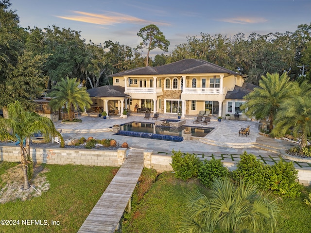 back of property featuring a patio, a balcony, a fire pit, an in ground hot tub, and a gazebo