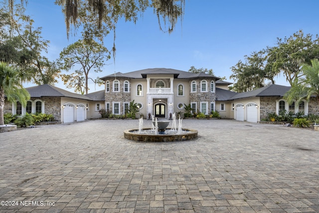 view of front of property featuring an attached garage, stone siding, and decorative driveway