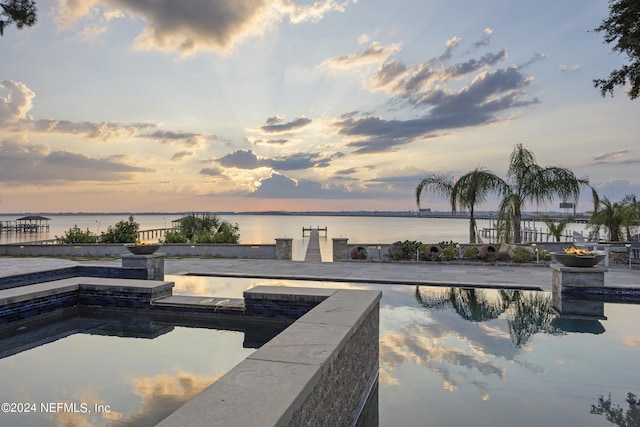 pool at dusk featuring a water view