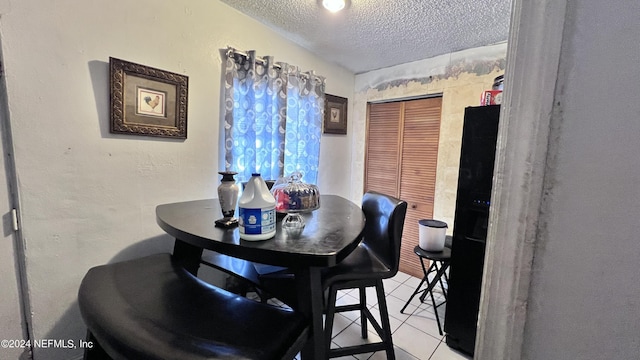 dining area featuring a textured ceiling, a textured wall, and light tile patterned floors