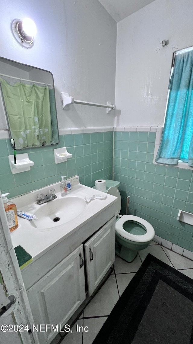 bathroom featuring tile walls, toilet, wainscoting, vanity, and tile patterned floors