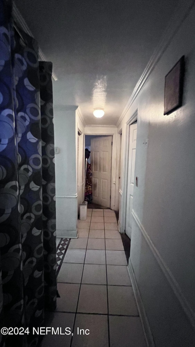 hallway with ornamental molding and tile patterned floors