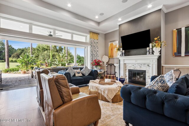 living room with hardwood / wood-style flooring, a tray ceiling, a tile fireplace, and ornamental molding