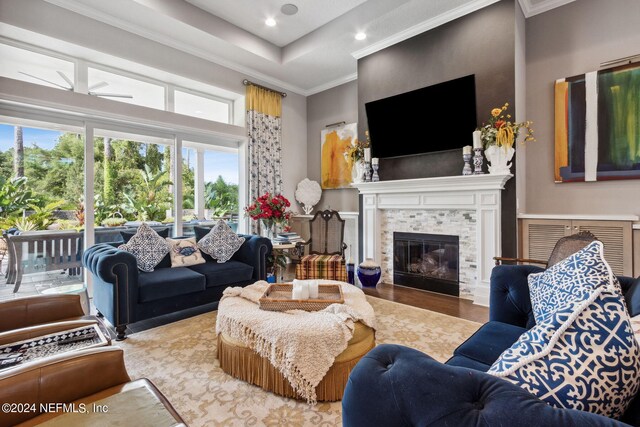 living room featuring hardwood / wood-style flooring, a raised ceiling, a high ceiling, and ornamental molding