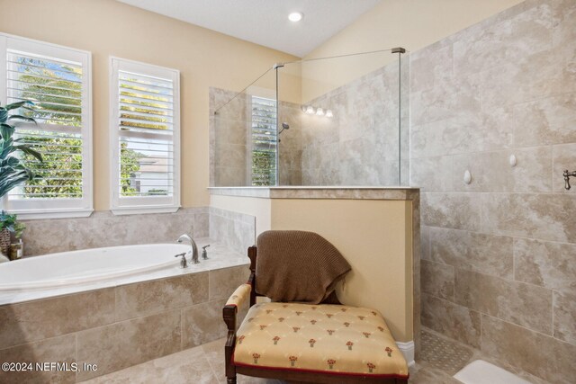 bathroom featuring a wealth of natural light, tile patterned flooring, separate shower and tub, and vaulted ceiling