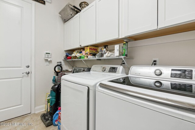 laundry area with washing machine and clothes dryer, cabinets, and light tile patterned floors