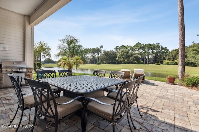 view of patio featuring exterior kitchen, area for grilling, and a water view