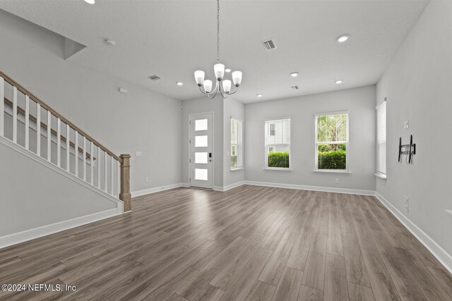 unfurnished living room with an inviting chandelier and hardwood / wood-style floors