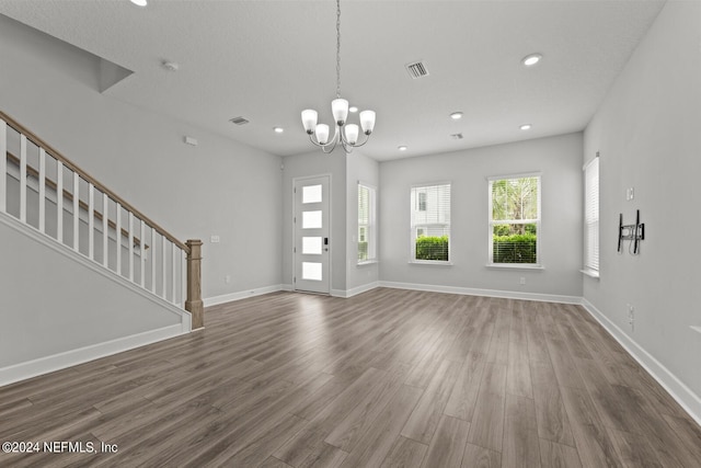 interior space featuring a textured ceiling, dark wood-type flooring, and a notable chandelier