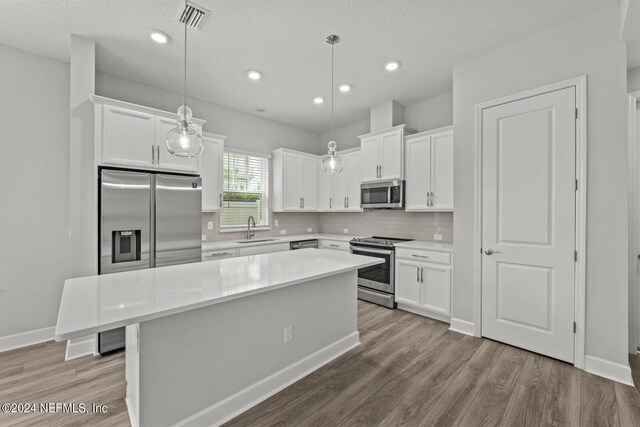 kitchen with light wood-type flooring, a center island, stainless steel appliances, and sink