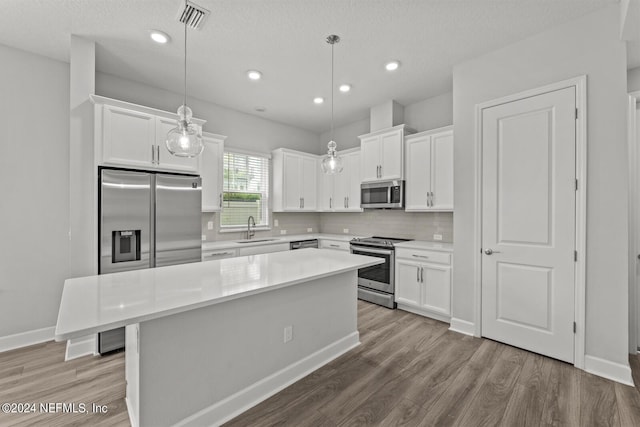 kitchen with sink, appliances with stainless steel finishes, hanging light fixtures, and a center island