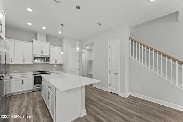 kitchen with white cabinetry, a kitchen island, stainless steel appliances, and decorative light fixtures