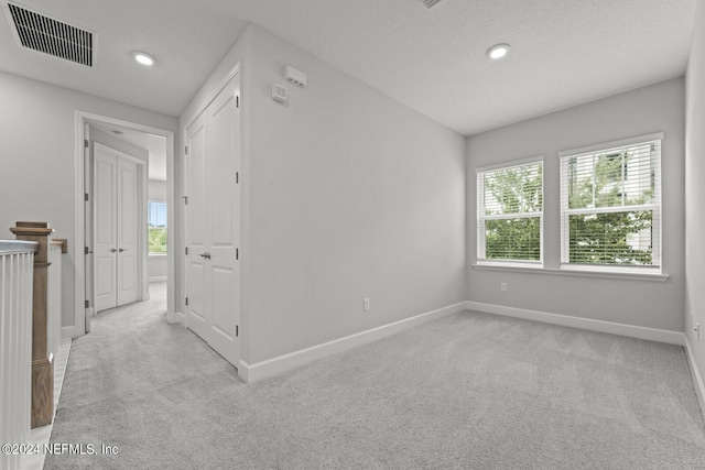 interior space with a textured ceiling and light colored carpet