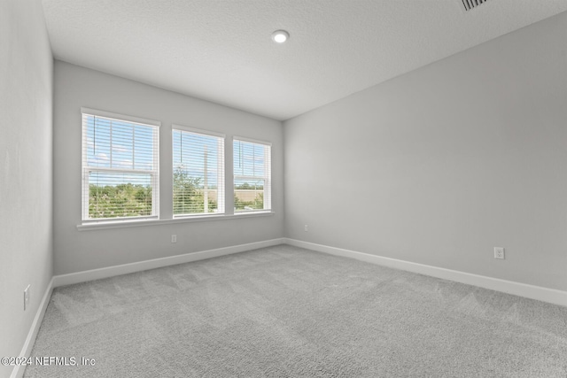 carpeted empty room with a textured ceiling