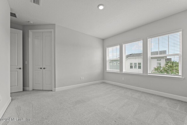 empty room featuring a textured ceiling and light carpet