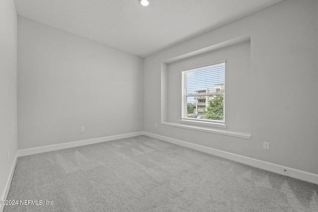 unfurnished room featuring light carpet and a textured ceiling